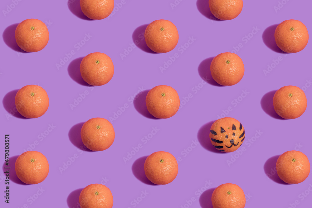 Tangerine pattern on violet background with tiger face drawn on one tangerine. Chinese New Year minimal flat lay visual.