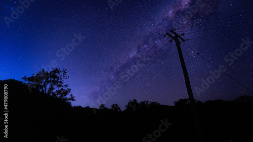 horizontal shot of some silhouette of trees, bushes and electric post of wires at dawn with stars photo