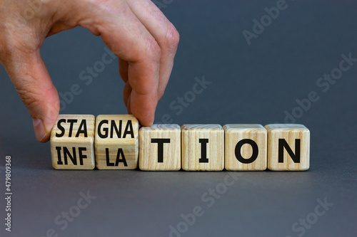 Inflation and stagnation symbol. Businessman turns cubes, changes the word inflation to stagnation. Beautiful grey table, grey background, copy space. Business, inflation and stagnation concept. photo