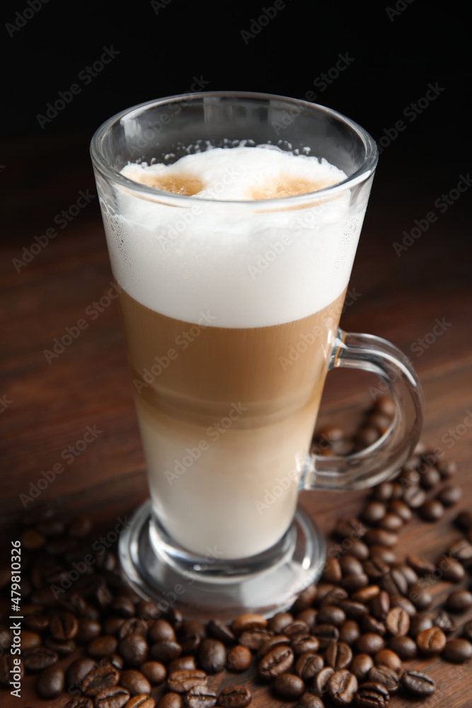 Delicious latte macchiato and coffee beans on wooden table Delicious latte macchiato and coffee beans on wooden table