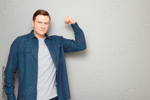 Portrait of serious charismatic man raising clenched fist up