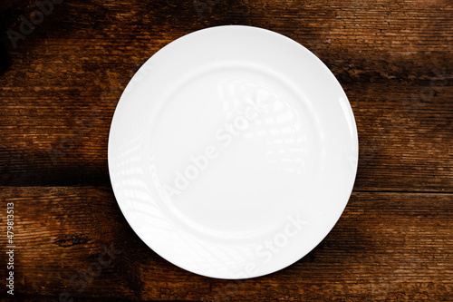 Empty white plate on a wooden background. Top view.