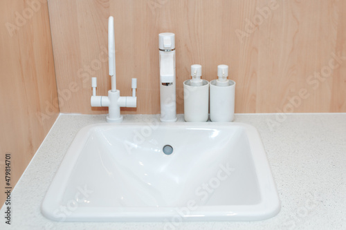Modern kitchen white faucet and ceramic kitchen sink. Minimalist bathroom interior details