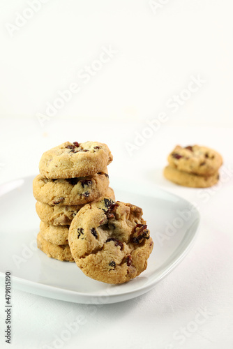 Biscotti al mirtillo rosso con gocce di cioccolato bianco su sfondo bianco.