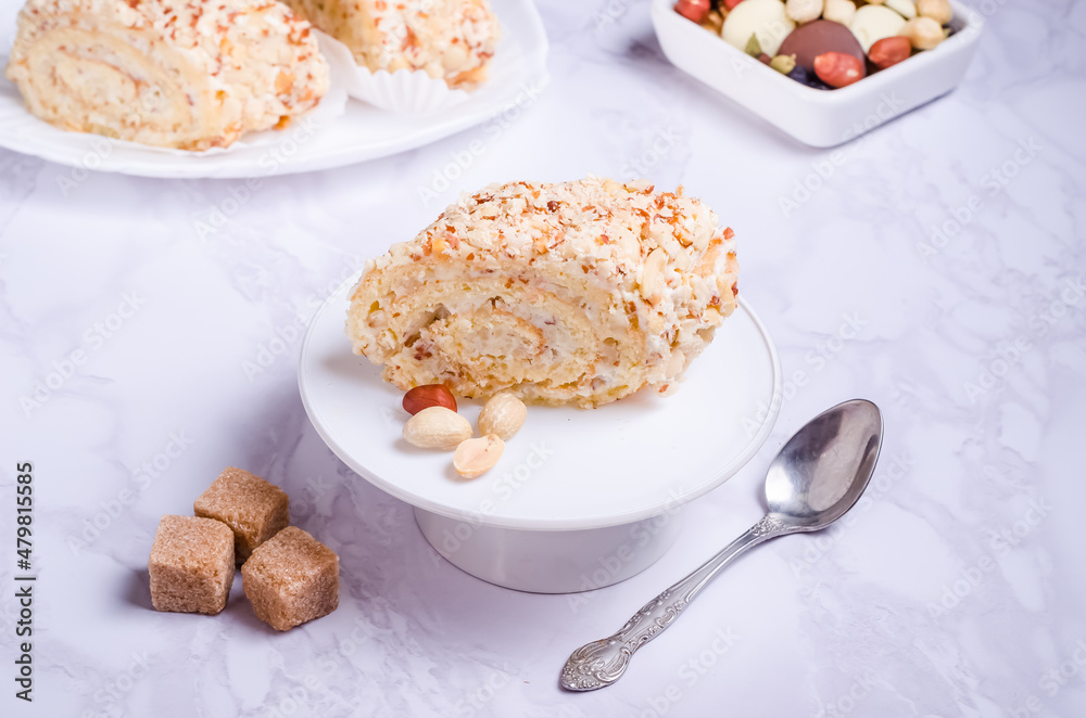 Cake roll with peanuts with cream on a white plate