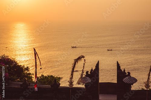 Traditional Balinese boats sailing at the dawn as seen from the Pura Luhur Uluwatu, Uluwatu Temple a Balinese Hindu sea temple on the hill, Bali, Indonesia.