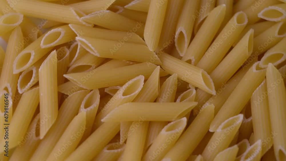 Close up of raw Italian penne pasta, rotating. Uncooked traditional food. Mediterranean cuisine Close up of raw Italian penne pasta, rotating. Uncooked traditional food. Mediterranean cuisine
