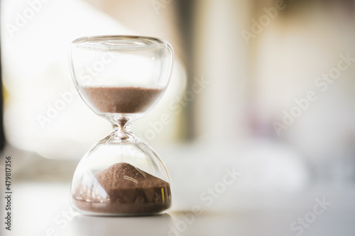 Hourglass on a wooden table convey memories with the passing of time, selective focus.