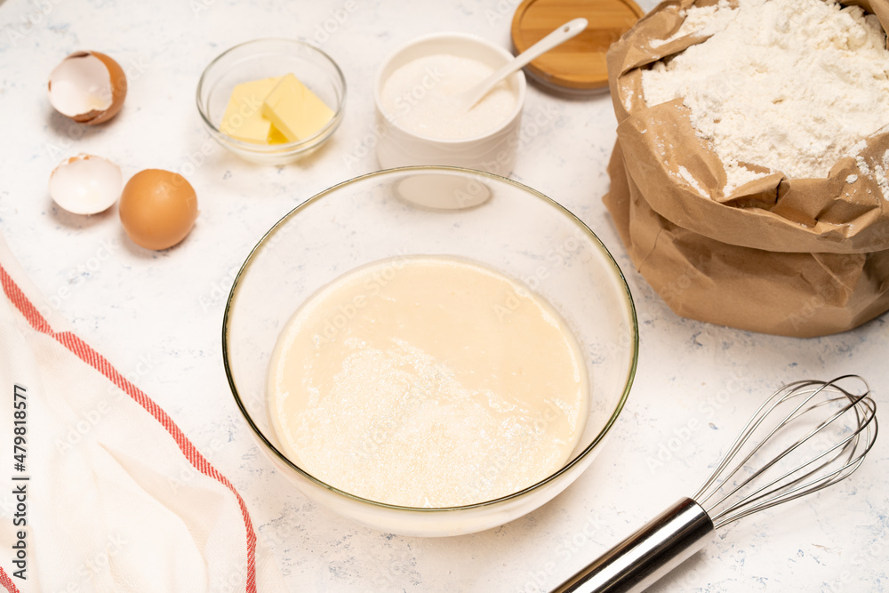 the process of making dough for pancakes with ingredients on a light table, eggs and flour are whipped with a mixer the process of making dough for pancakes with ingredients on a light table, eggs and flour are whipped with a mixer