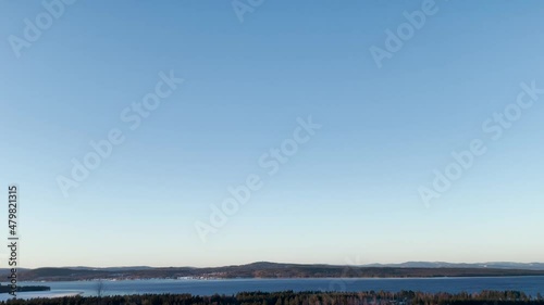 Panoramic view of winter landscape on a cold tranquil morning. Sunrise over lake Siljan and the mountains in the distant. Footage made at Tällberg in Dalarna, Sweden. photo