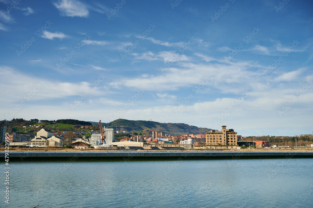 View of the Nervion river in the foreground and the industrial zone of Zorroza with a blue sky with clouds