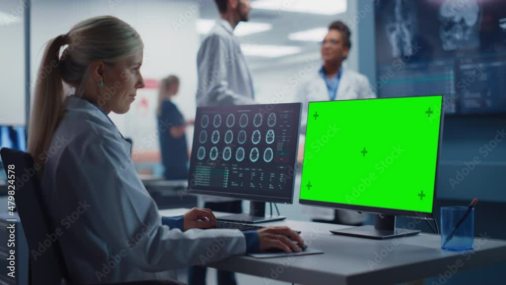 Hospital Research Lab: Female Medical Biotechnology Scientist Working on Green Screen Chroma Key Computer with Brain Scan MRI Images. Background: Neuroscientists Have Meeting Analysing MRI Scan Hospital Research Lab: Female Medical Biotechnology Scientist Working on Green Screen Chroma Key Computer with Brain Scan MRI Images. Background: Neuroscientists Have Meeting Analysing MRI Scan