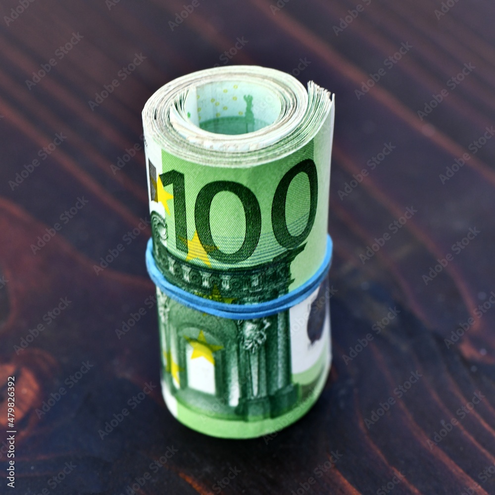 Roll of  1000 Euro in 100 Euro banknotes isolated on wood background