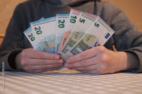 Twenty, ten and five euro banknotes in hand. A person counts money.