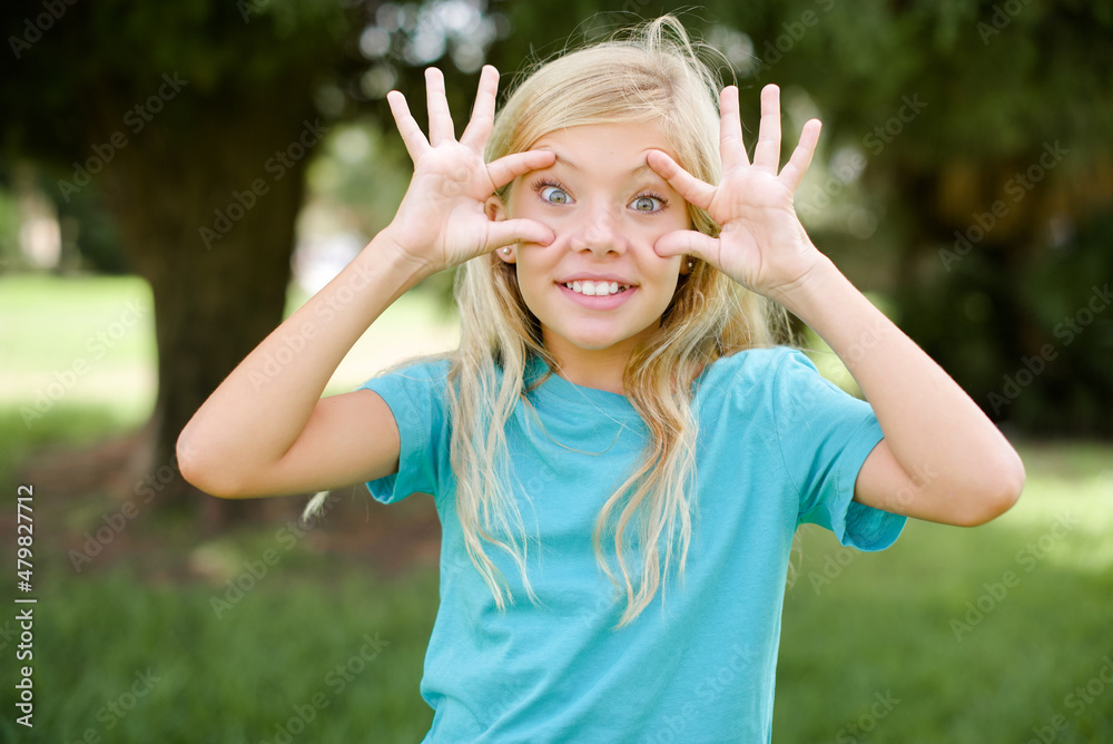 Caucasian little kid girl wearing blue T-shirt standing outdoors keeping eyes opened to find a success opportunity.