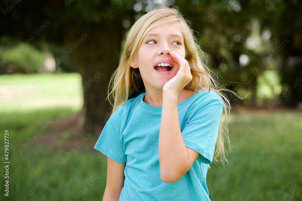 Caucasian little kid girl wearing blue T-shirt standing outdoors hear incredible private news impressed scream share Caucasian little kid girl wearing blue T-shirt standing outdoors hear incredible private news impressed scream share