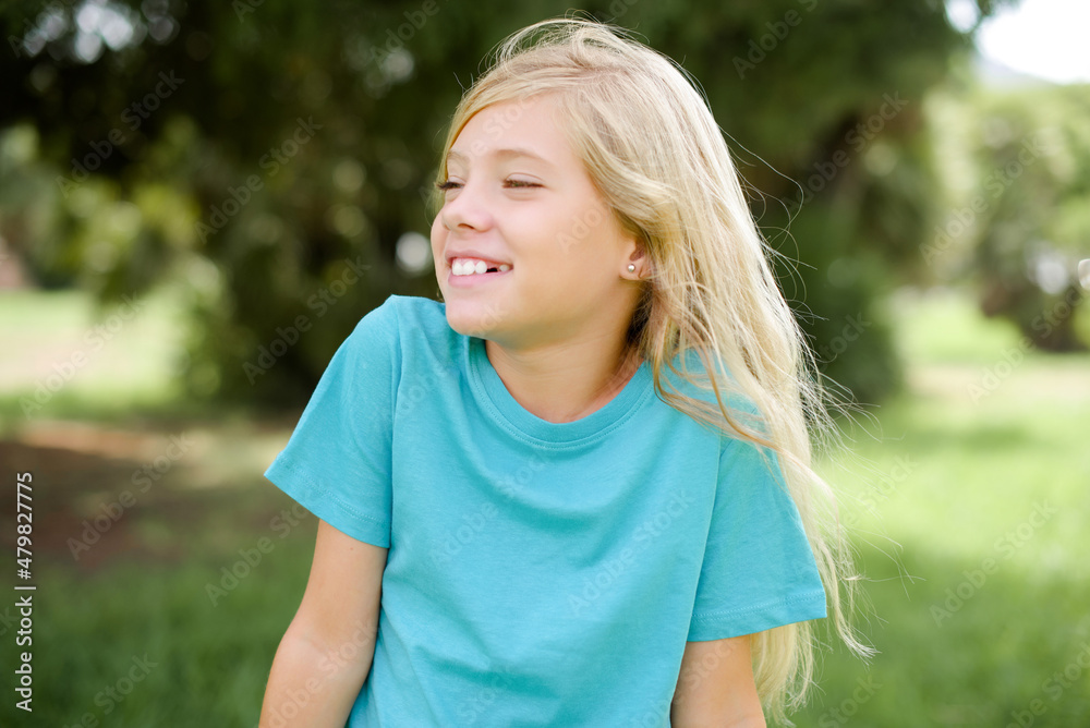 Caucasian little kid girl wearing blue T-shirt standing outdoors very happy and excited about new plans. Caucasian little kid girl wearing blue T-shirt standing outdoors very happy and excited about new plans.