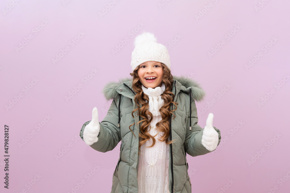 Smiling child in warm clothes with curly hair is ready for a cold winter. winter season and snowfall. baby is very happy about the new warm clothes.