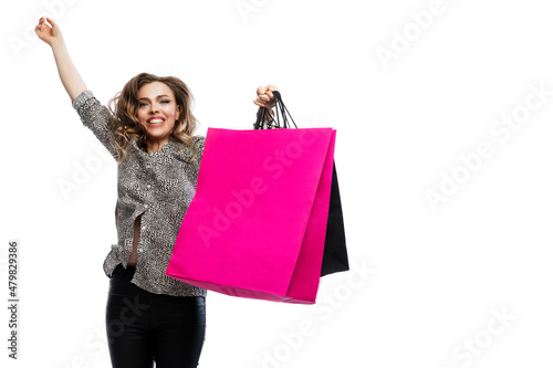 Joyful woman with multi-colored paper bags from shops is jumping. Beautiful blonde. Shopping, fashion and style. Isolated on white background. Space for text.
