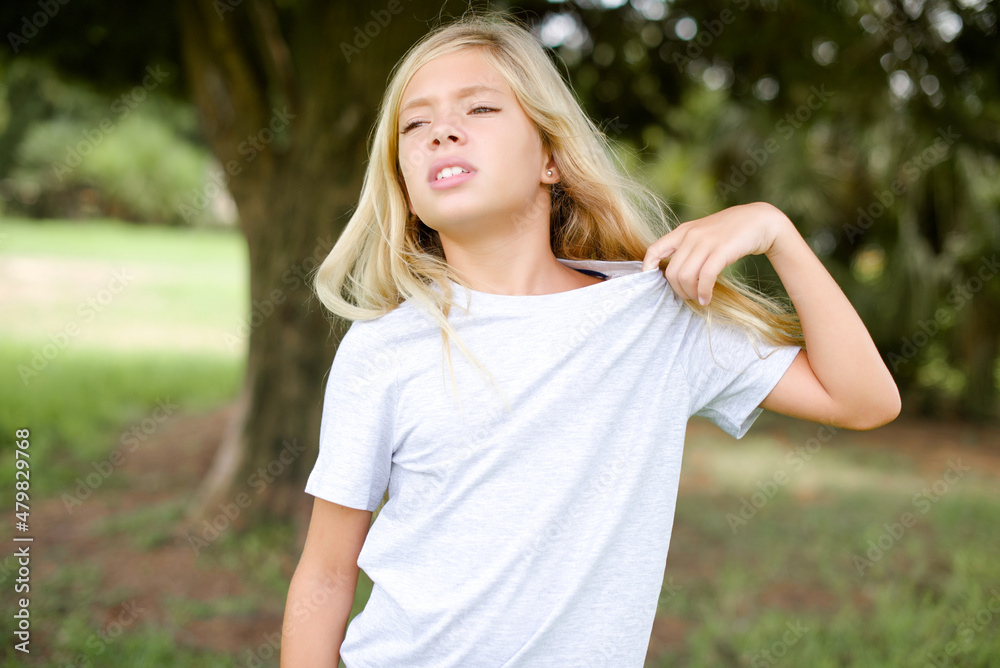 Caucasian little kid girl wearing whiteT-shirt standing outdoors stressed, anxious, tired and frustrated, pulling shirt neck, looking frustrated with problem Caucasian little kid girl wearing whiteT-shirt standing outdoors stressed, anxious, tired and frustrated, pulling shirt neck, looking frustrated with problem