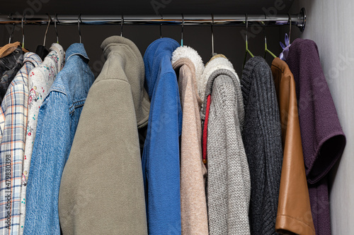 various clothes hanging on a hanger in a wardrobe