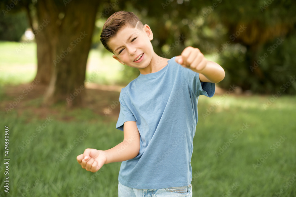 beautiful Caucasian little kid boy wearing blue T-shirt standing outdoors imagine steering wheel helm rudder passing driving exam good mood fast speed beautiful Caucasian little kid boy wearing blue T-shirt standing outdoors imagine steering wheel helm rudder passing driving exam good mood fast speed