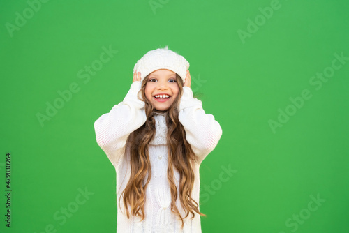A little girl with long curly hair is very happy about the winter season. Warm winter clothes for a beautiful girl. Baby in a warm sweater.