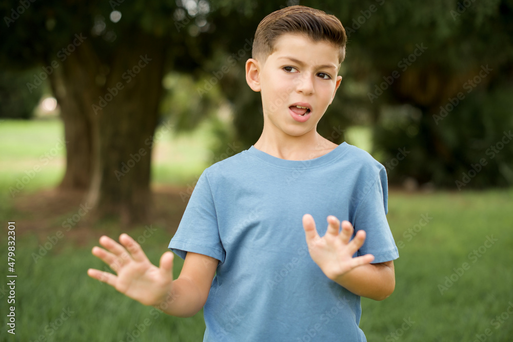 Caucasian little kid boy wearing blue T-shirt standing outdoor afraid and terrified with fear expression stop gesture with hands, shouting in shock. Panic concept. Caucasian little kid boy wearing blue T-shirt standing outdoor afraid and terrified with fear expression stop gesture with hands, shouting in shock. Panic concept.