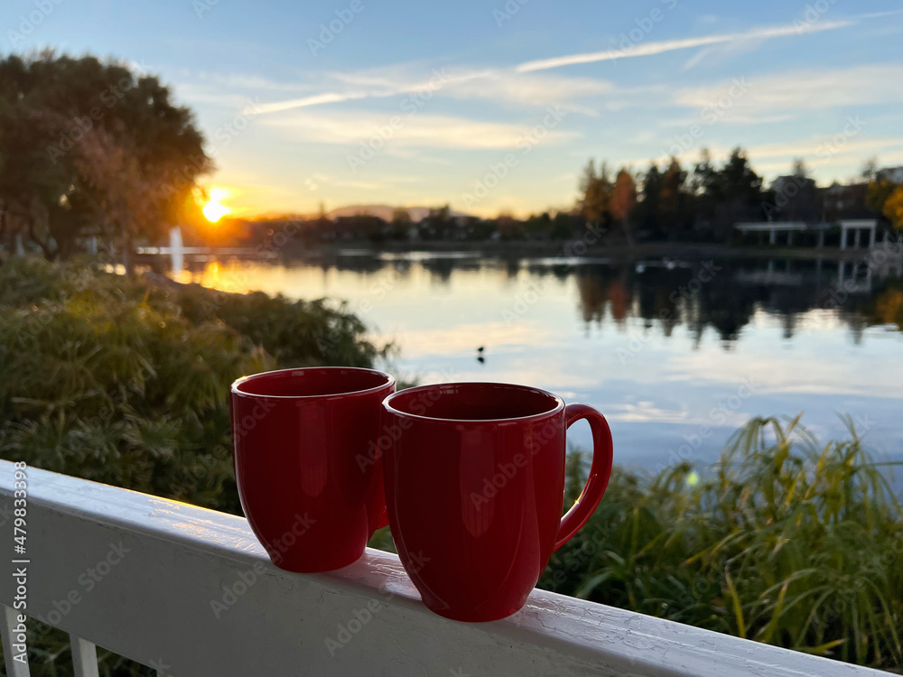 Obraz premium Coffee cup with beautiful sunrise and lake in the background.