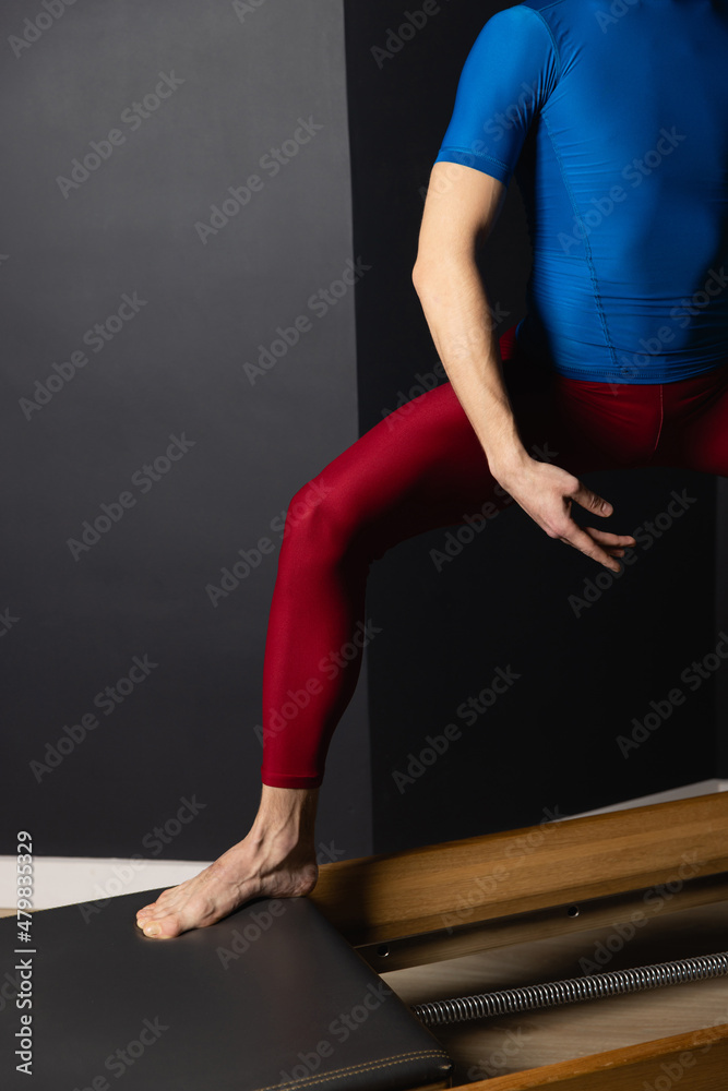 Sporty man doing exercises on pilates reformer training machine. Working out wearing sportswear, gym. Sporty man doing exercises on pilates reformer training machine. Working out wearing sportswear, gym.