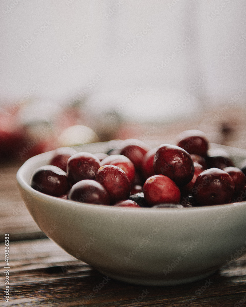 Bowl of fresh cranberries in front of white blurry background. Bowl of fresh cranberries in front of white blurry background.