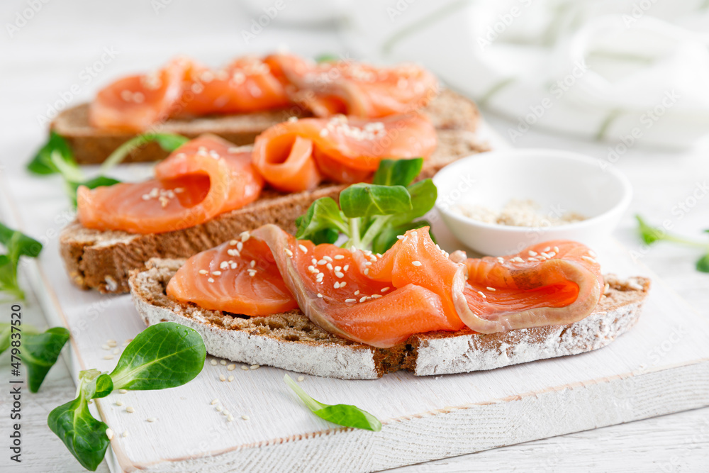 Whole grain rye bread open sandwiches with salted salmon on a white rustic wooden table. Healthy food Whole grain rye bread open sandwiches with salted salmon on a white rustic wooden table. Healthy food