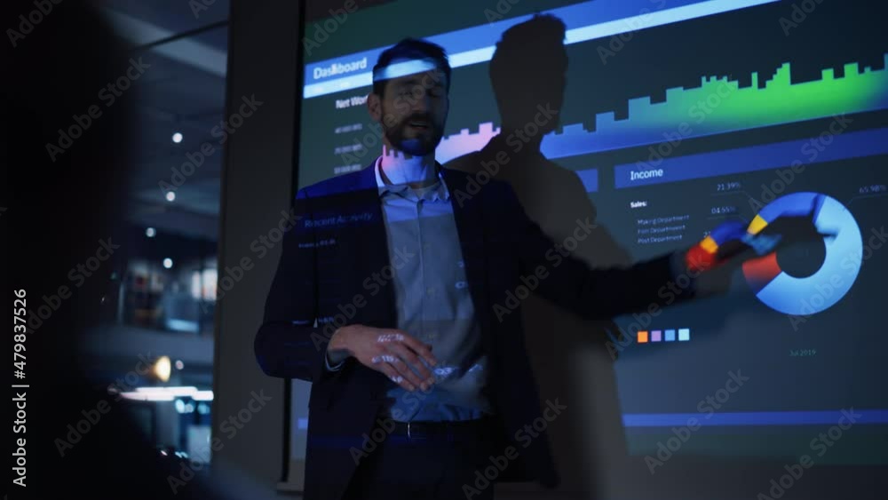 Conference Business Meeting Presentation: CEO Businessman Shows Data to Group of Investors, Businessspeople. Projector Screen Shows Graphs, Product Sales, Revenue Growth Strategy, e-Commerce Analysis