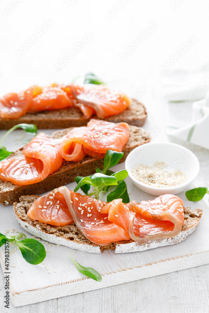Whole grain rye bread open sandwiches with salted salmon on a white rustic wooden table. Healthy food Whole grain rye bread open sandwiches with salted salmon on a white rustic wooden table. Healthy food