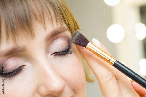 The make-up artist puts shadows on the eyelids. Makeup. Female face model with fashionable makeup, beauty concept.