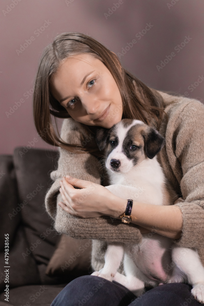 A girl hugs a small white mongrel puppy sitting on her lap