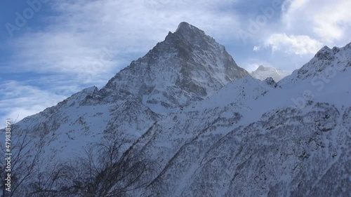 Wallpaper Mural High mountain peak, mountains in winter, trees on mountain slopes, white clouds over mountains, clouds in blue sky, cold winter weather, mountain climbing, climbing, snow-capped rocks, peaked mountain Torontodigital.ca