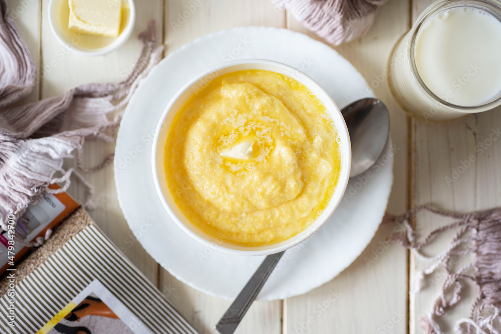 Healthy breakfast: milk corn porridge in a white plate on a white table. Top view. Healthy breakfast: milk corn porridge in a white plate on a white table. Top view.