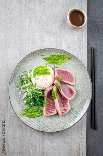 Traditional Japanese tuna tataki fillet with rice, wakame and wasabi cream served as top view on a Nordic design plate photo