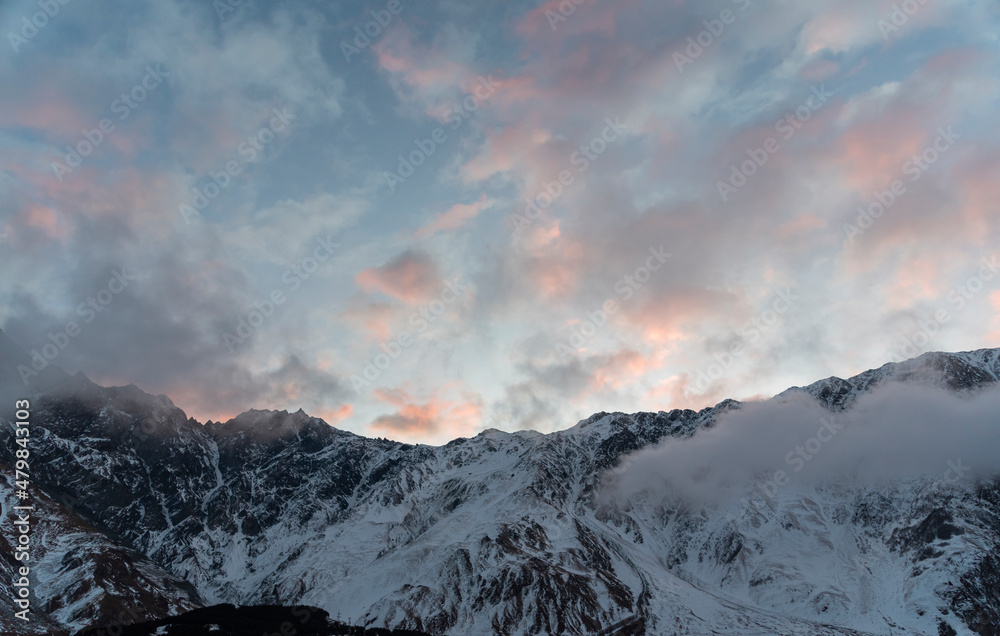 Beautiful winter mountains landscape on the sunrise. High snow covered mountains in the fog. Georgia, Kazbegi.
