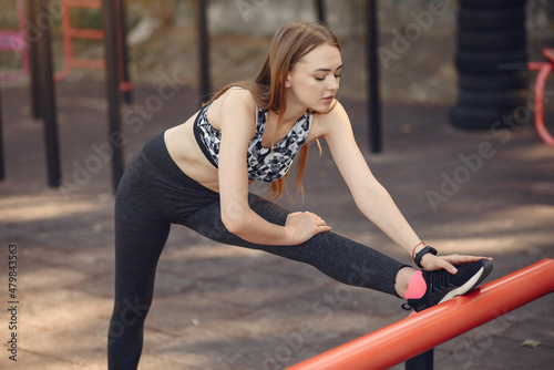 Sports girl in a black top training in a summer park