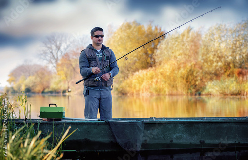 Fisherman standing in the boat and angling on the river. Sport and recreation concept