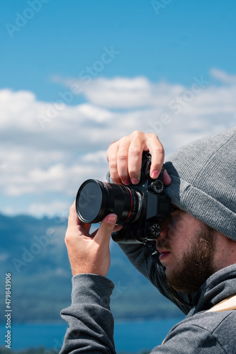Portrait of a photographer taking a picture with his hand on the camera.  Focusing and shooting photography in daylight. 