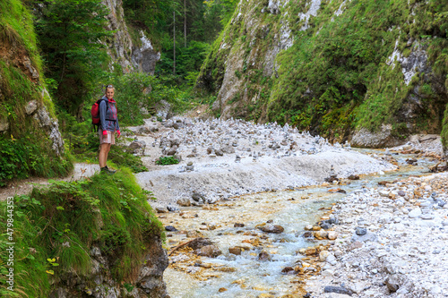 young woman is hiking along the river Martuljški towards zgornji Waterfall, spik mountain, Slovenia