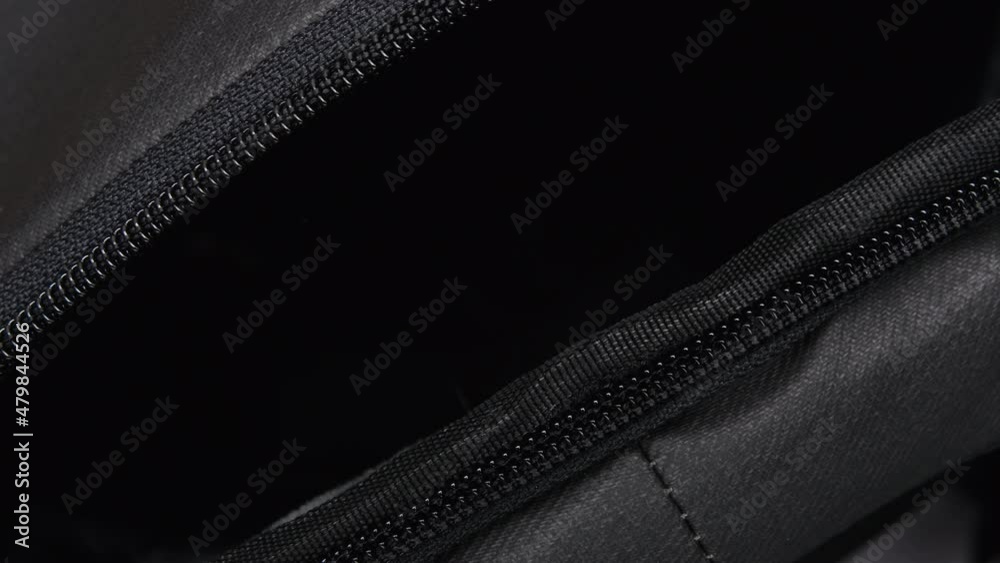 A Man's Hand Zips And Unzips A Black Travel Backpack With A Zipper. Close-up Of The Zipper Of The Travel Bag. Open And Close The Zipper Of The Bag Top View. Macro Shot A Man's Hand Zips And Unzips A Black Travel Backpack With A Zipper. Close-up Of The Zipper Of The Travel Bag. Open And Close The Zipper Of The Bag Top View. Macro Shot