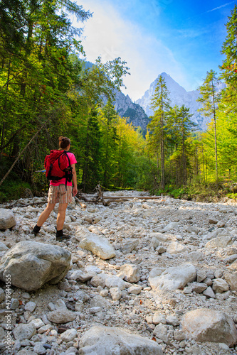 young woman is hiking the Martuljški riverbed to Zgornji Waterfall, Slovenia