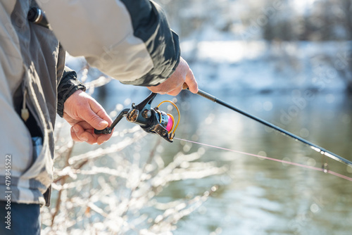 Fotografia Fishing on the river in winter, the fisherman holds a fishing rod in his hands a