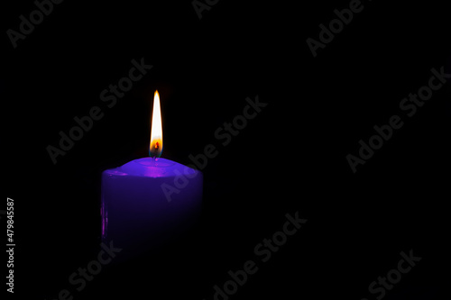 one candle burns in the dark