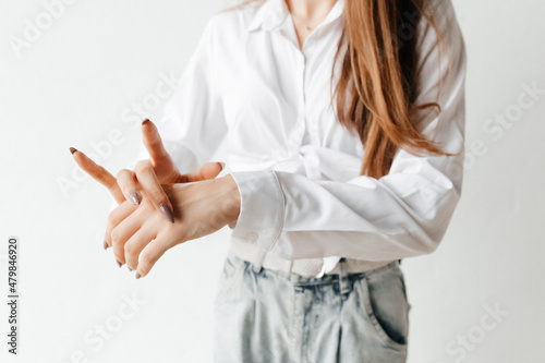 Woman in white shirt spreading hand cream over her hand. Close up. cold season hands skin protection. closeup woman applying protective cream on hands.