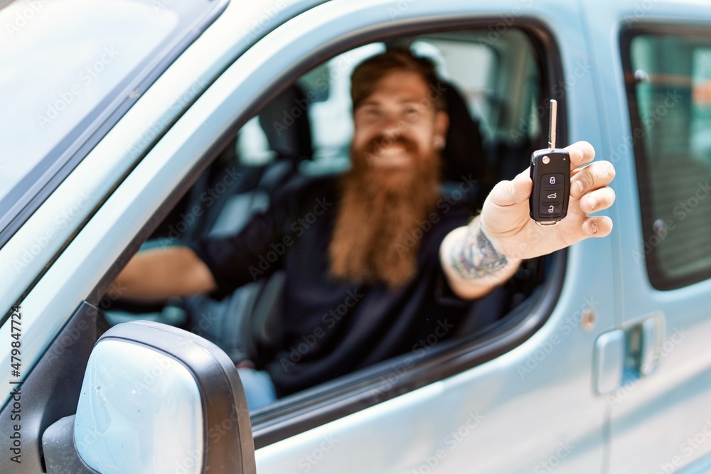 Young irish man smiling happy sitting on the car holding key at the city. Young irish man smiling happy sitting on the car holding key at the city.